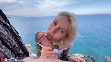 Блондинка в татуировках сосет парню на берегу с видом на океан